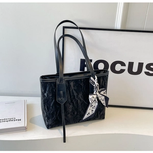 Detail of black tote bag with pleated leather texture and decorative fashion silk scarf