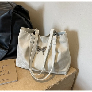 Detail of white marble textured tote bag featuring a metallic silver butterfly charm