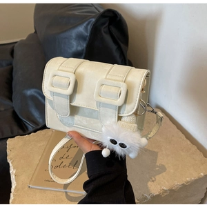 Detail view of cream vintage satchel bag with oversized square buckle and monster charm