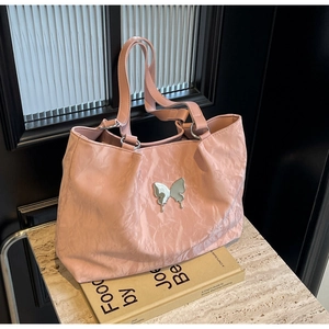 Detail of pink pleated leather tote bag featuring a metallic silver butterfly ornament