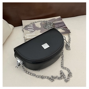 Detail shot of black semi-circular saddle bag with silver clasp and metal chain strap