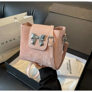 Detail of pink bucket bag with a large silver metallic bow and adjustable leather strap