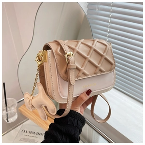 Gros plan sur le sac bandoulière matelassé beige avec logo doré et bijou de sac