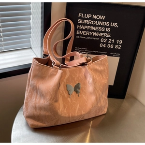 Detail of light pink tote bag featuring crinkled texture and silver butterfly ornament