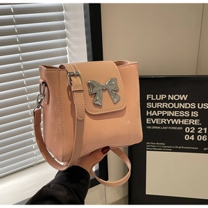 Pink bucket bag with a metallic silver bow accent and adjustable shoulder strap detail
