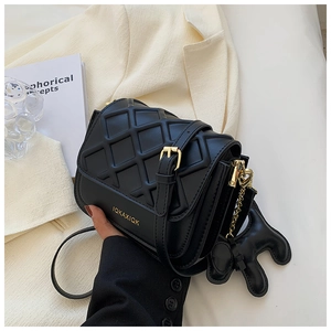 Détail du mini sac matelassé noir avec boucle dorée et pendentif chiot élégant