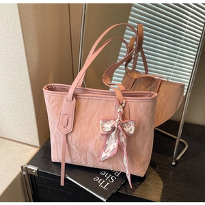 Detailed shot of pink tote bag with textured finish and fashion scarf bow on handle