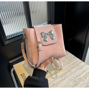 Close-up of pink bucket bag with silver bow ornament and textured leather finish