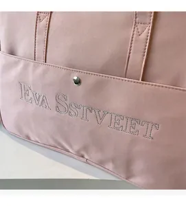 Detail der rosa Canvas-Reisetasche mit EVA SSTVEET-Stickerei und silbernem Metalldruckknopf