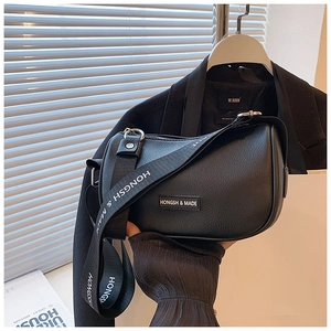 Detail of black lychee grain leather crescent bag with branded wide fabric shoulder strap
