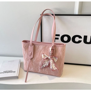 Detail of light pink tote bag featuring crinkled texture and decorative silk scarf bow