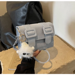 Detail of light blue crossbody bag with matte texture and cute monster plush charm