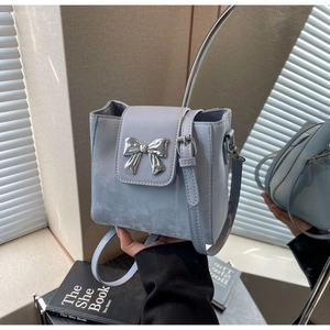 Close-up of light blue leather crossbody bag with elegant silver metal bow buckle