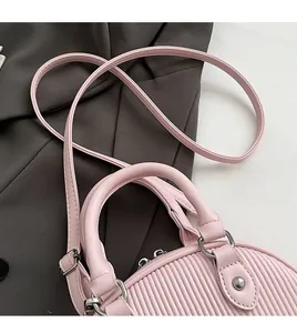 Dettaglio della texture plissettata rosa in pelle PU con anelli argento e tracolla