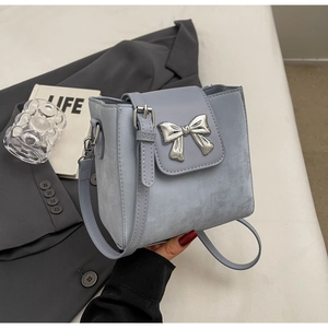 Close-up of light blue leather crossbody bag featuring a silver metal bow accent