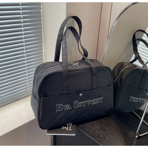 Detail der schwarzen Nylon-Reisetasche mit weißer Stickerei und Magnet-Fronttasche