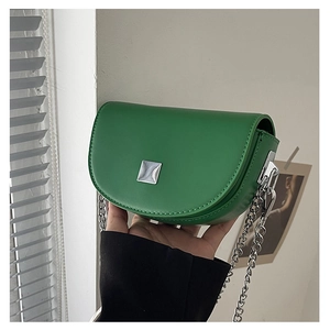 Detailed close-up of green matte leather saddle bag featuring silver chain and metal buckle