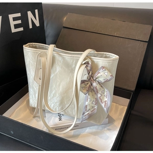 Macro shot of cream white tote bag featuring crinkled leather texture and fashion silk scarf