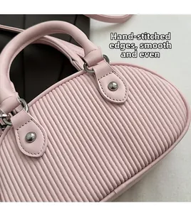 Dettaglio ravvicinato della mini borsa rosa a pieghe con anelli in metallo e cuciture