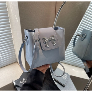 Detailed view of light blue bucket bag with silver bow clasp and adjustable strap
