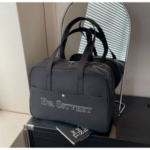 Detailansicht der schwarzen Reisetasche aus Segeltuch mit Stickerei und Metalldruckknopf