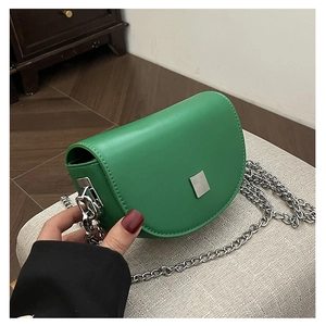 Detail of green leather saddle bag featuring a silver metal lock and chain strap