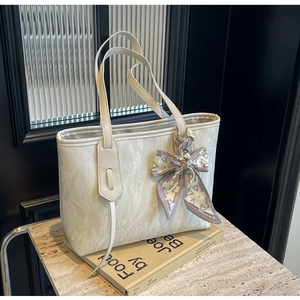 Detailed macro view of white textured tote bag featuring a decorative fashion silk scarf