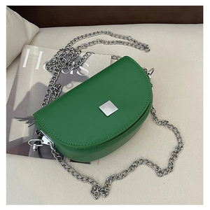 Detail of green crescent saddle bag with silver chain strap and matte leather finish