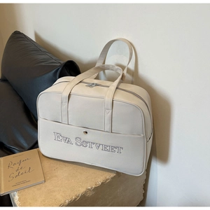 Detail der minimalistischen cremefarbenen Reisetasche mit Lederstruktur und Prägung