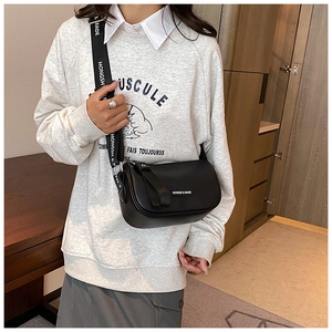 Detail of black leather crossbody bag with branded wide strap shown on model