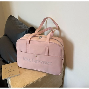 Detail der Stickerei auf der Vordertasche einer rosa Reisetasche mit Magnetverschluss