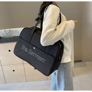 Detailansicht der großen schwarzen Canvas-Reisetasche mit weißem Stick und Metallschnalle