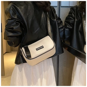 Detail of cream crossbody bag with black trim and branded nylon shoulder strap