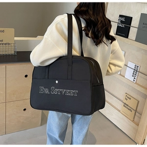 Rückansicht eines Modells mit einer großen schwarzen Reisetasche aus Nylon mit Logo