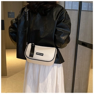 Detail of minimalist cream PU leather crossbody bag with bow accent and logo strap