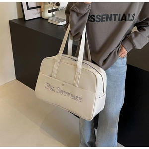 Detail der cremefarbenen Reisetasche mit EVA SSTVEET Aufdruck und Doppelgriffen