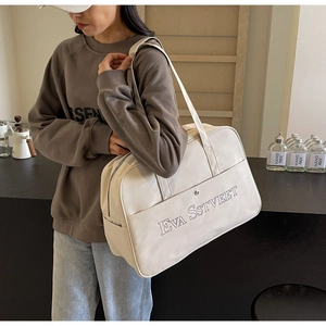 Detailansicht der cremefarbenen Segeltuchtasche mit Stickerei, getragen am Modell