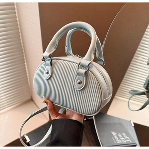 Dettaglio della mini borsa azzurra con trama plissettata verticale e rivetti argento