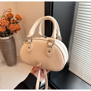 Dettaglio mini borsa a tracolla crema con texture a pieghe verticali e fibbie argento