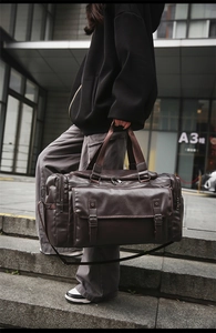 Detail of a large brown faux leather travel bag with vintage texture and front flap pocket