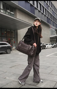 Detail of dark brown leather travel bag featuring retro buckle pockets and high-capacity design