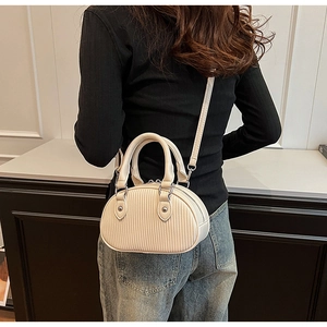 Vista posteriore di una modella con borsa a tracolla crema e rilievo a righe verticali
