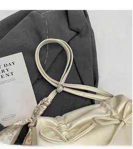 Detail of cream pleated shoulder bag with bow decor and heart-print silk scarf handle