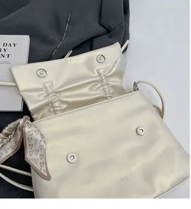 Close-up of cream shoulder bag featuring magnetic closure and decorative heart scarf