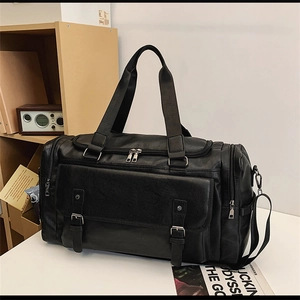 Detail of black large travel bag showing pebbled leather texture and dual buckle pocket