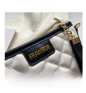 Close-up of quilted cream bucket bag with black trim and elegant gold chain detail