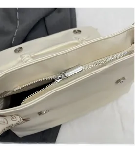 Close-up of silver zipper and magnetic buckle closure on a white tote bag with silk scarf