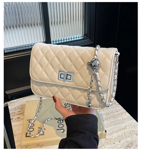 Detail der cremeweißen Stepptasche mit Silberverschluss und verstellbarer Metallkugel