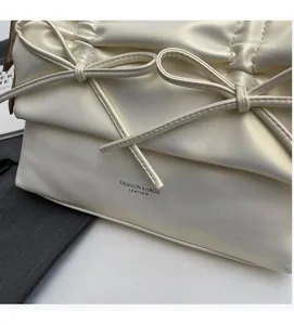 Close-up of cream leather tote bag featuring elegant double bows and pleated details