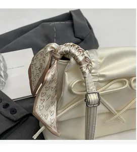 Close-up of cream tote bag featuring a heart-print silk scarf wrapped around the handle